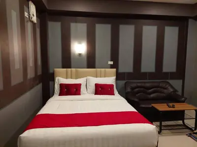 a bedroom with a large bed and a leather chair at BB GuestHouse in Ban Zong Katiam