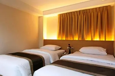three beds in a room with yellow curtains at Gateway Hotel Pratunam in Bangkok