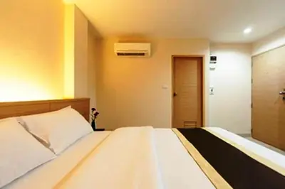 a bedroom with a large white bed and a door at Gateway Hotel Pratunam in Bangkok