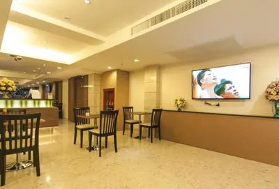 a waiting room with tables and chairs and a flat screen tv at Gateway Hotel Pratunam in Bangkok
