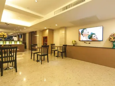 a waiting room with tables and chairs and a flat screen tv at Gateway Hotel Pratunam in Bangkok