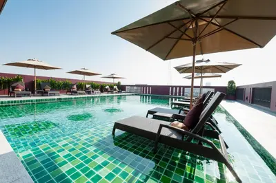 a swimming pool with chairs and umbrellas on a building at Casa Nithra Bangkok in Bangkok
