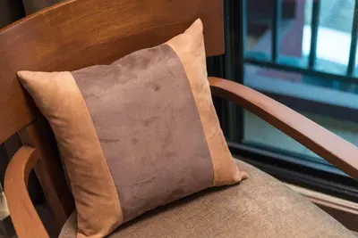 a brown pillow sitting on a wooden chair at Casa Nithra Bangkok in Bangkok