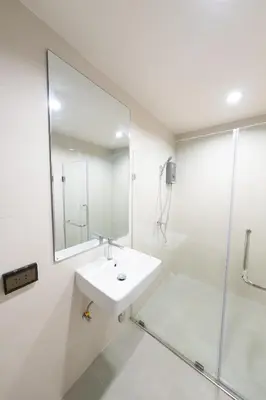a white bathroom with a sink and a shower at L.A. Tower Hotel in Bangkok