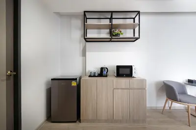 a small kitchen with a refrigerator and a microwave at The Riski Hotel at Bangphlat Station SHA in Bangkok