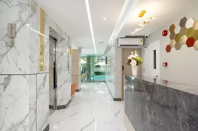 a lobby with white marble walls and a hallway at The Riski Hotel at Bangphlat Station SHA in Bangkok
