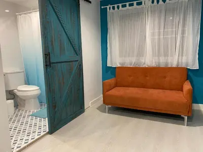 a bathroom with an orange chair and a toilet at Grasshopper Bed and Cafe in Pak Kret