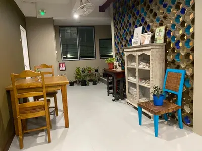 a dining room with a table and chairs and a table and a shelf at Grasshopper Bed and Cafe in Pak Kret