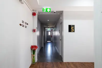 a hallway in a building with a number sign and flowers at 185@Surawong Residence in Bangkok