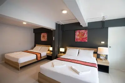 a bedroom with two beds and a painting on the wall at 185@Surawong Residence in Bangkok