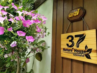 a sign for a nature house with pink flowers at 37 Nature House in Bangkok