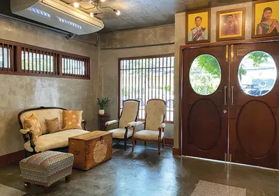 a living room with chairs and a wooden door at Niagara Hotel in Bangkok