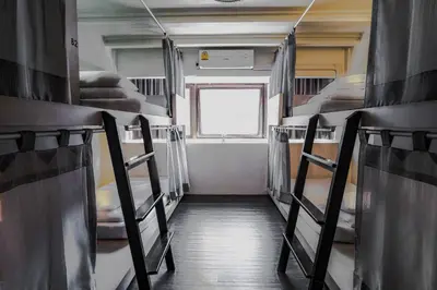 an empty train room with bunk beds and a window at 3Howw Hostel @ Sukhumvit 21 in Bangkok