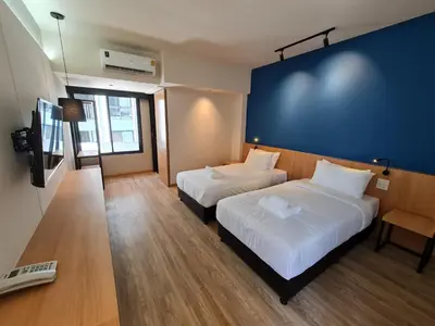 a hotel room with two beds and a television at The Neuf@Ratchada in Bangkok