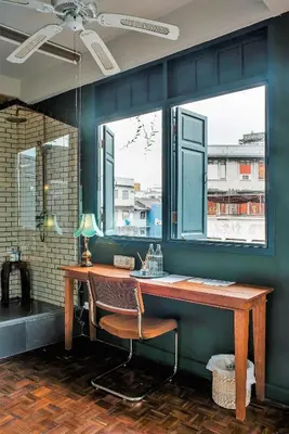 a desk with a chair in a room with two windows at Ba Hao Residence in Bangkok