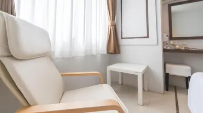 a white room with a chair and a table at Pas Cher Hotel de Bangkok in Bangkok