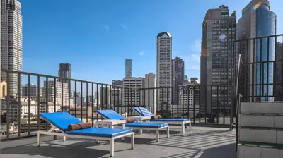 a group of blue chairs on a balcony with a city skyline at Pas Cher Hotel de Bangkok in Bangkok