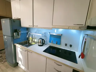 a kitchen with white cabinets and a sink and a refrigerator at Harmony family room in Bangkok