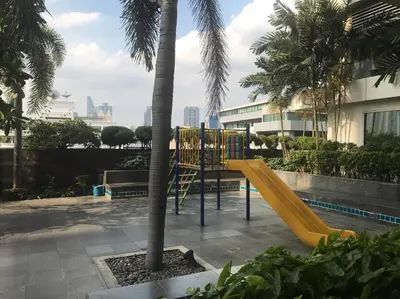 a playground with a yellow slide next to a palm tree at Harmony family room in Bangkok