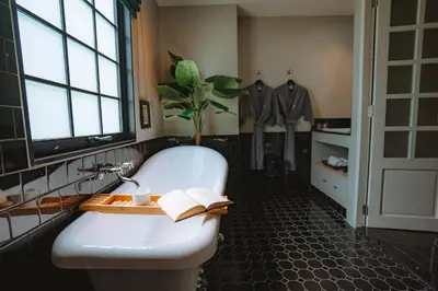 a bathroom with a tub and a plant and a book at Hotel Thomas Bangkok in Makkasan