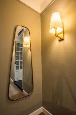 a mirror on a wall with a light on it at Hotel Thomas Bangkok in Makkasan