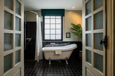 a bathroom with a tub and a window at Hotel Thomas Bangkok in Makkasan