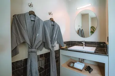 a bathroom with a sink and a robe on a rack at Hotel Thomas Bangkok in Makkasan