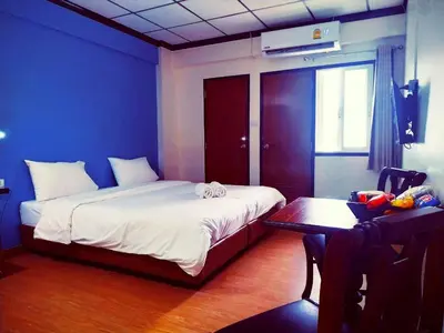 a bedroom with a bed and a desk and a table at Beerapan Hotel in Bangkok
