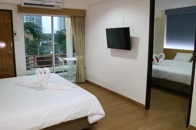 a hotel room with two beds and a flat screen tv at Beerapan Hotel in Bangkok