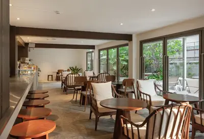 a restaurant with tables and chairs and windows at Nidhra Boutique Hotel Bangkok Sukhumvit in Bangkok