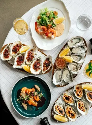 a table with plates of oysters and other foods at The Standard, Bangkok Mahanakhon in Bangkok