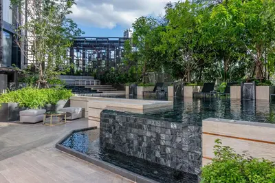 a fountain in a courtyard with trees and a building at Gardina Asoke Hotel & Residence in Bangkok