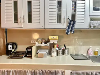 a kitchen counter with white cabinets and a sink at Dara Three Hostel ดาราตรี in Bangkok