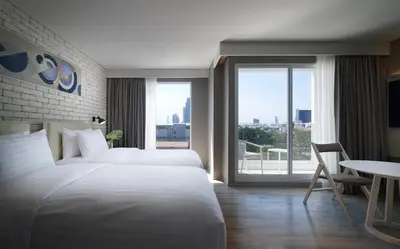 a hotel room with two beds and a large window at Shama Yen-Akat Bangkok in Bangkok
