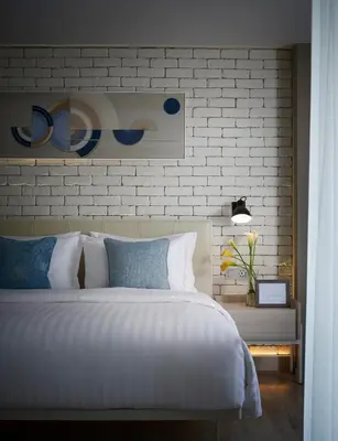 a bedroom with a large bed and a brick wall at Shama Yen-Akat Bangkok in Bangkok