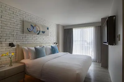 a bedroom with a white bed and a brick wall at Shama Yen-Akat Bangkok in Bangkok