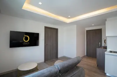 a living room with a couch and a tv on a wall at ORION Hotel & Residence Bangna in Bangkok