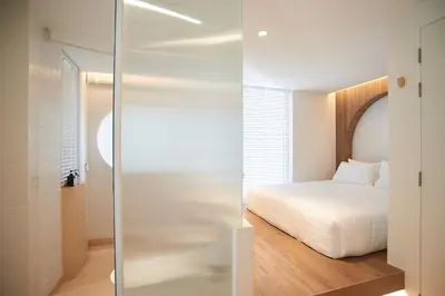 a bedroom with a bed and a glass shower door at Bonsai Hotel Bangkok in Bangkok