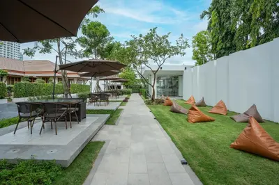 a garden with tables and chairs and an umbrella at Away Bangkok Riverside Kene in Bangkok