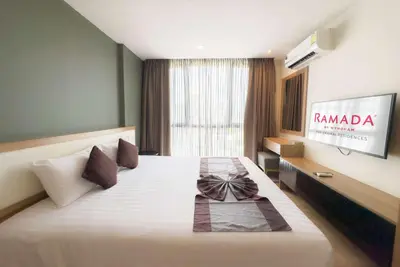 a hotel room with a large bed with a television at Ramada Ekamai in Bangkok