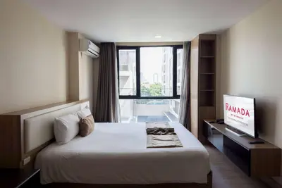 a hotel room with a bed and a window at Ramada Ekamai in Bangkok