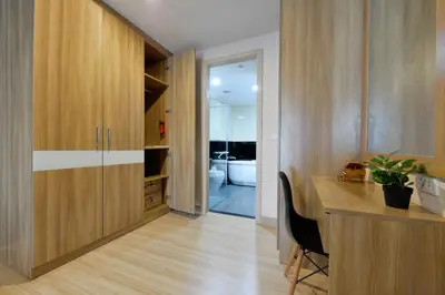 a kitchen with wooden cabinets and a desk with a plant at Ramada Ekamai in Bangkok