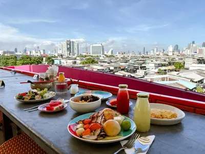a table with plates of food and a view of a city at The Fig Lobby Bangkok in Bangkok
