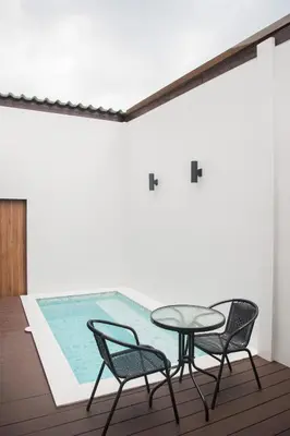 a patio with a table and chairs next to a swimming pool at VEVILLA in Bangkok
