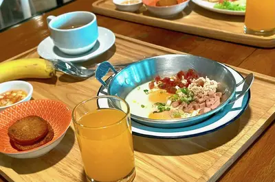 a table with a bowl of breakfast food and a bowl of orange juice at The Plimplace Hotel in Bang Su