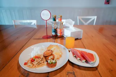 two plates of breakfast food on a wooden table at The Plimplace Hotel in Bang Su