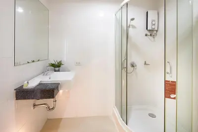 a white bathroom with a sink and a shower at The Plimplace Hotel in Bang Su