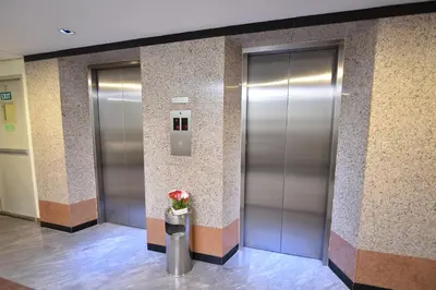 a lobby with two elevators with a vase of flowers at Bangkok City Suite in Bangkok