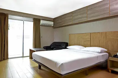 a bedroom with a large white bed and a chair at Watana Hotel in Bangkok
