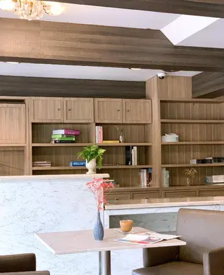 a dining room with a table and bookshelves at Watana Hotel in Bangkok